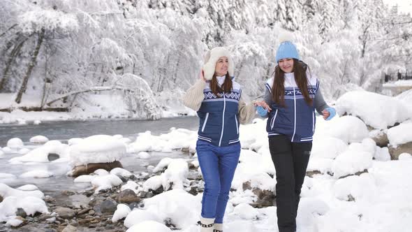 Two Girls in Love Walk Near the River in a Snowy Forest alt