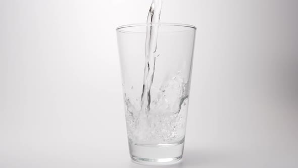 Clear water pour into a transparent glass on a white background