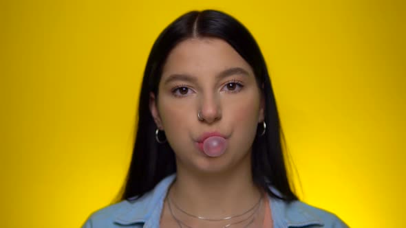 Young Woman Blowing Bubble Gum Ball in Slow Motion Looking at Camera Portrait