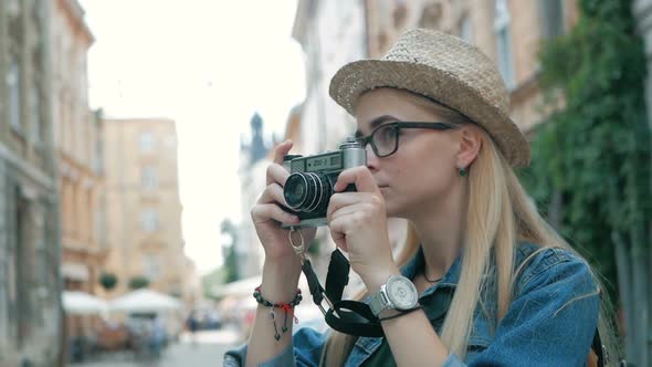 Young woman tourist taking a picture on retro camera of a city on vacation