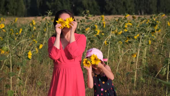 Mother with Daughter Have Fun in Sunflowers Field alt