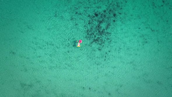 High aerial view of two young girls swimming and playing in sea with inflatables. alt