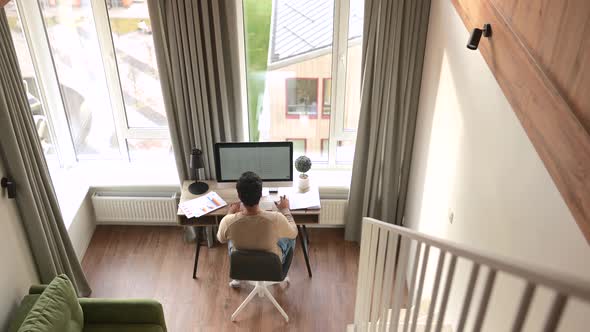 Back View of the Clever and Concentrated Caucasian Guy is Doing Paperwork alt