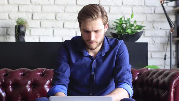 Concentrated serious entrepreneur man working on laptop at home office, thinking of inspiration solv alt
