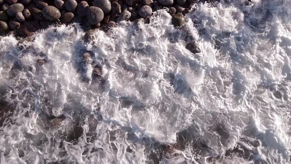 Winter Aerial Flight Top Over Waves Rolling on Artic Ocean Shore with Round Stones Ocean Waves at alt