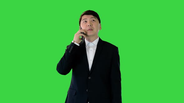 Asian Man in Office Suit Talking on Mobile Phone on a Green Screen Chroma Key alt