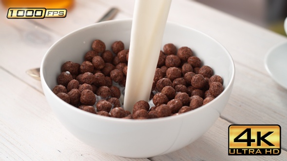 Pouring Milk into Bowl of Chocolate Ball-Shaped Cereals alt