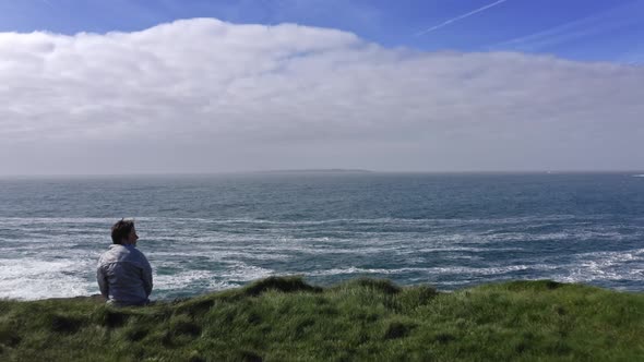 Aerial View of Young Woman Sitting on the Meadow Cliff Admiring the Beautiful Irish Landscape Rough