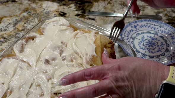 Plating a freshly baked and iced cinnamon roll to eat alt