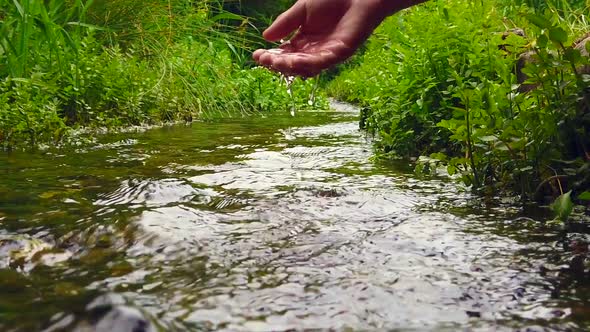 Girl playing with hand in the river. alt