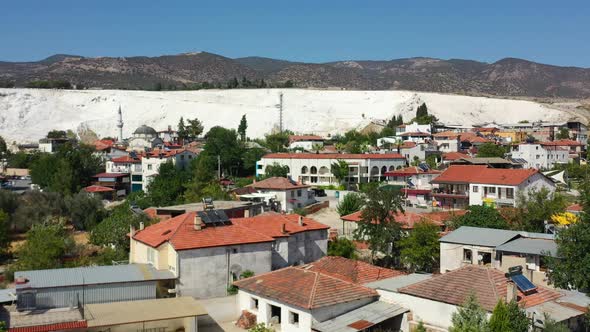 low aerial view of european homes in Pamukkale Turkey with a white mineral rich mountain and thermal alt