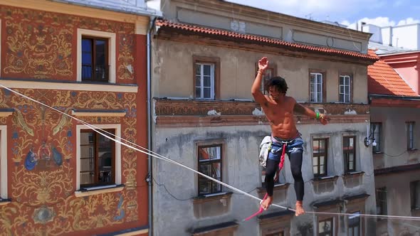 Man Balances on Tight Rope a View of the City From Height alt