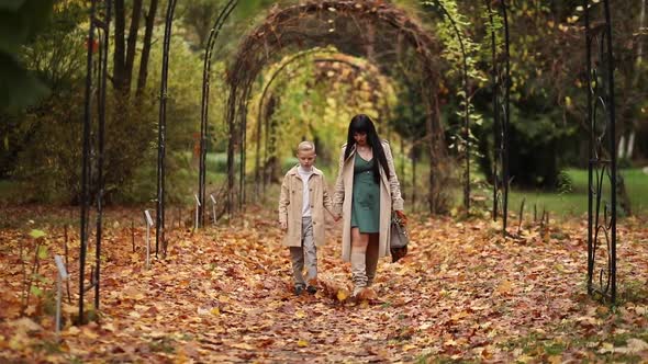 Mom and Son are Walking in the Park in Autumn