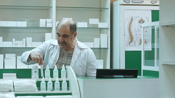 Senior male pharmacist with mustache posing at the drugstore
