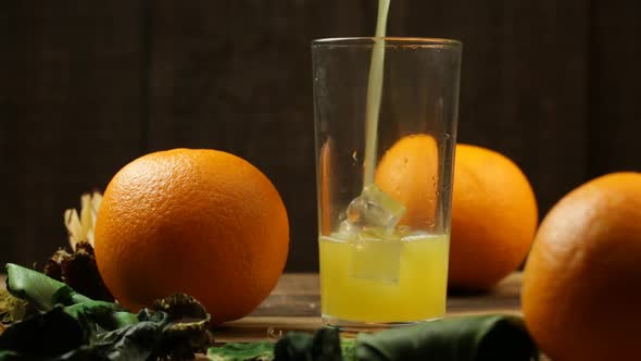 Orange Juice Is Poured Into A Glass With Ice Cubes And An Orange Is Close On The Table