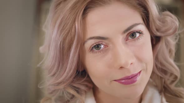 Close-up Face of Pretty Caucasian Girl with Curly Hair and Hazel Eyes Looking at Camera As Applying alt
