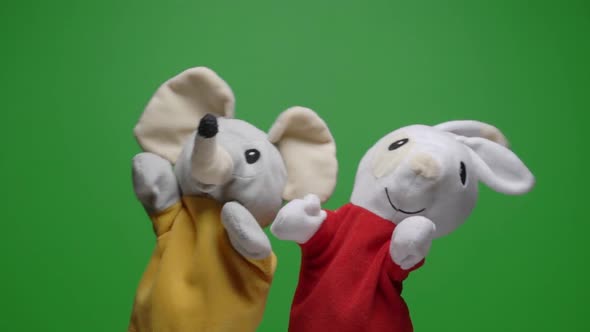 Funny soft dolls on green background, hand with plushie glove puppet toys alt