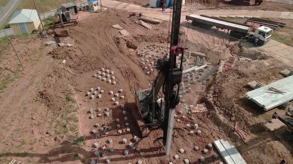 A Large Vertical Piledriving Crane Hammers Reinforced Concrete Piles Into the Ground at a alt