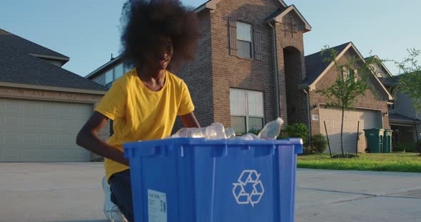 African American adolescence placing plastic bottles in recycle bin alt