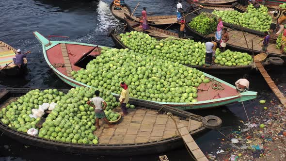 Aerial view of workers exchanging watermelons on boats along the Buriganga River. alt