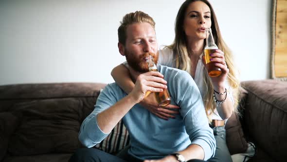 Happy Couple Drinking Beer and Toasting at Home
