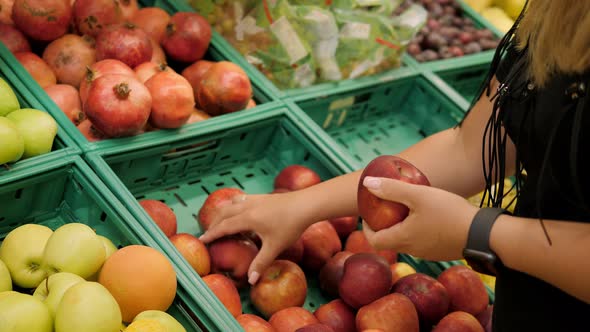 Closeup of a Young Woman Choosing Fresh Fruit in a Grocery Stores alt