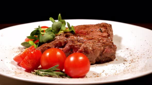 A Piece of Fried Meat Garnished with Cherry Tomatoes and Microgreen Rotating on a White Plate