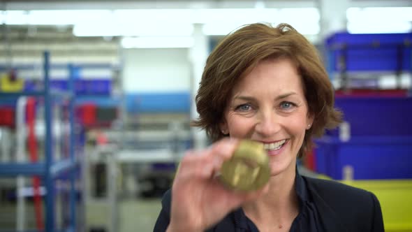 Female manager looking through metal part in factory alt