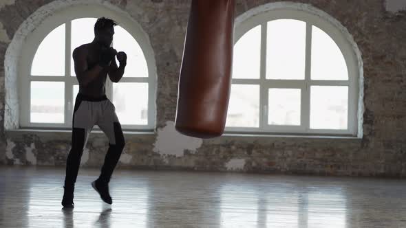 Shirtless Male Boxer Enjoying Training at Boxing Studio with Wrapped Hands alt