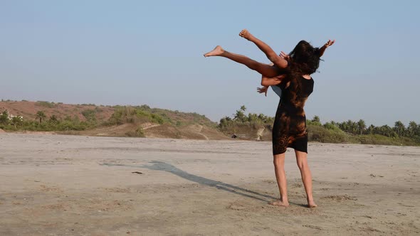 Mom Trains a Teen Daughter to Perform Acrobatic Element on the Beach