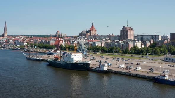 Fly Above River Along Waterfront with Parking Lot with Ferris Wheel Amusing Attraction alt