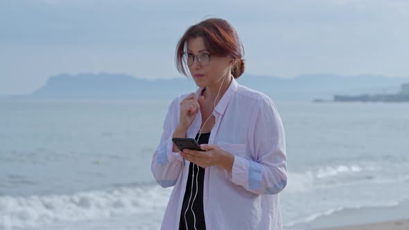 Serious Woman Talking on Video Call Using Smartphone with Headphones