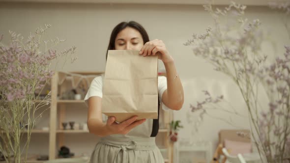 Craftswoman Showing Paper Bag in Pottery Studio