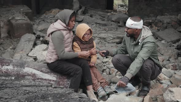 Refugees Sitting in Ruins of Demolished House alt