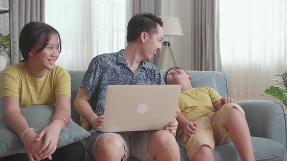 Happy Father With Two Little Children Using Laptop Together, Sitting On Sofa At Home alt