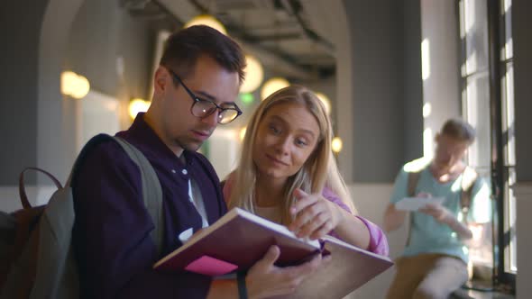 Portrait of Two Students Reading Notebook in Corridor Preparing for Exam alt