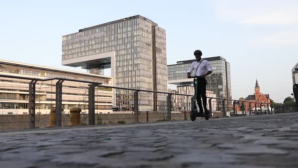 Modern businessman riding an e-scooter alt