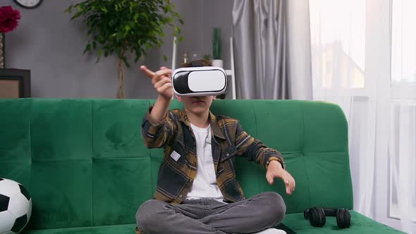Modern Teen Boy Sitting on Soft Green couch and Using Special Futuristic 3d Glasses to Play alt