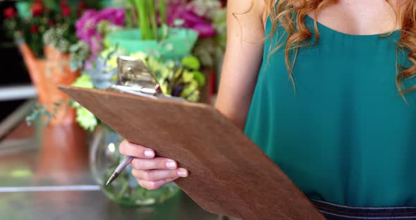 Female florist taking an order on mobile phone alt