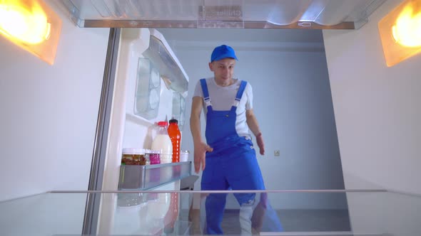 the refrigerator repairman is dancing an erotic dance. View from inside . alt