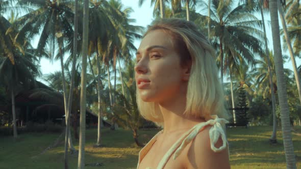 Young Blonde Standing Contemplating Tropical Rainforest Sunset Light Coming From Above alt
