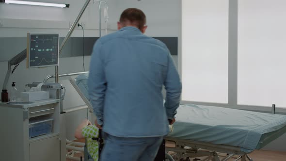 Young Father Supporting Pregnant Wife From Wheelchair alt