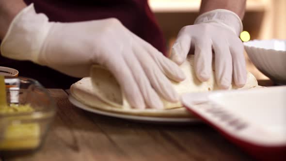Caucasian Cook Puts the Salad Filling Into Tortilla for Finished Enchilada in Restaurant Kitchen alt