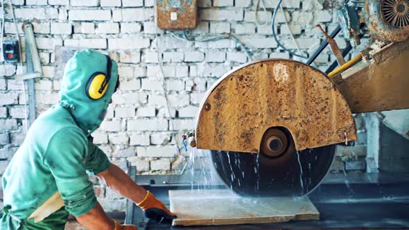 Man worker is putting stone slab into the CNC machine in factory. alt