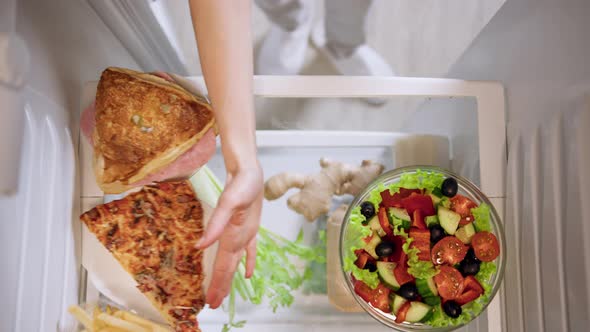 Woman's hand pushes aside unhealthy food and chooses green salad.