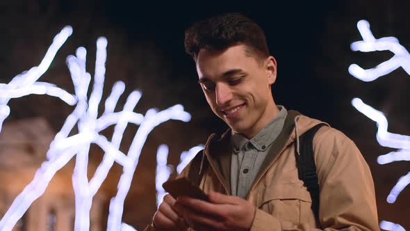 Portrait of Social Networking User Guy 20s Laughing While Reading Internet Posts on Smartphone alt
