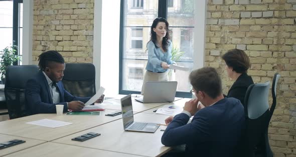 Confident Beautiful CEO Passing Documents To Colleagues and Talking. Portrait of Successful Young alt