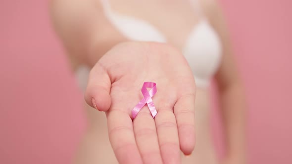 Close Up, Woman Holding Silk Pink Ribbon Between Her Fingers. Breast Cancer Awareness Month Pink alt