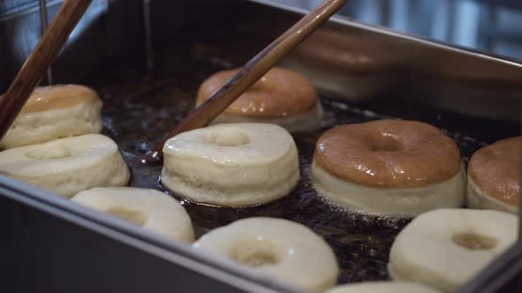 The Chef Is Turning the Donuts on Another Side with Sticks While Frying alt
