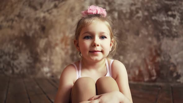 Sad Little Cute Baby Girl with Bows on Her Head Sitting on the Floor Crosslegged alt